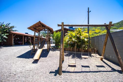um parque infantil com um escorrega e uma estrutura de madeira em Chalés do Parque Hospedagem em Penha