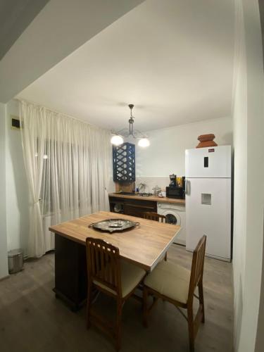 een keuken met een tafel en een witte koelkast bij Tori apartament in Târgu-Mureş