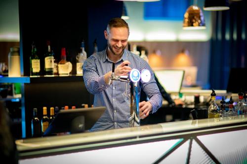 a man standing in front of a bar with a bottle of wine at Holiday Inn Express & Suites Queenstown, an IHG Hotel in Queenstown