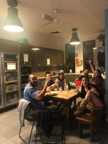 a group of people sitting around a table in a kitchen at EBS Sydney Hostel in Sydney