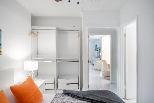 a bedroom with white walls and a bed with an orange pillow at Luxury Miami Condos - 1BR-2BR & 3BR in Miami Beach