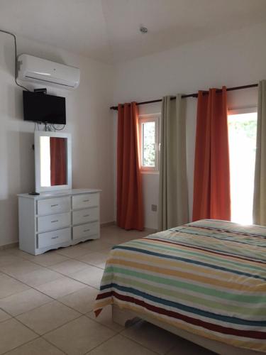 a bedroom with a bed and a dresser and a television at Apartamentos y Villas Michaela in Sosúa