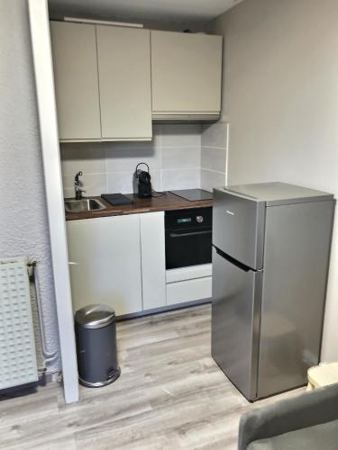 une cuisine avec des armoires blanches et un réfrigérateur en acier inoxydable dans l'établissement Appartement 4 personnes aux pieds des pistes Le Champame Wifi Netflix, à Les Deux Alpes