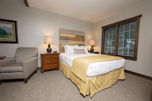 a bedroom with a bed and a chair and a window at Corduroy Inn and Lodge, Trademark Collection by Wyndham in Snowshoe