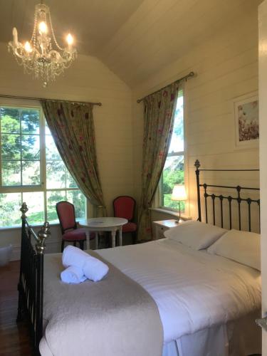 1 dormitorio con 1 cama, 2 sillas y lámpara de araña en Quamby Homestead, en Woolsthorpe