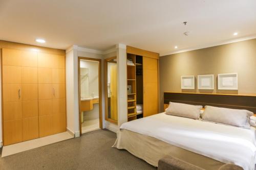 1 dormitorio con 1 cama blanca grande y baño en (103)Flat Executive Jardins (Apt. particular), en São Paulo