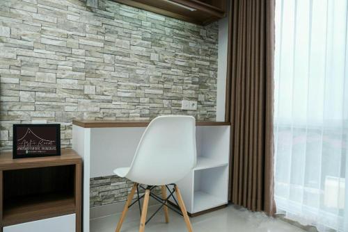 a white chair in a room with a brick wall at Apartemen Taman Melati Yogyakarta by ArFe Room in Sleman