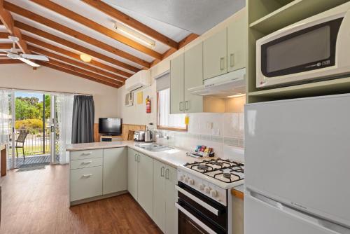 a kitchen with white cabinets and a stove top oven at Discovery Parks - Moama West in Moama