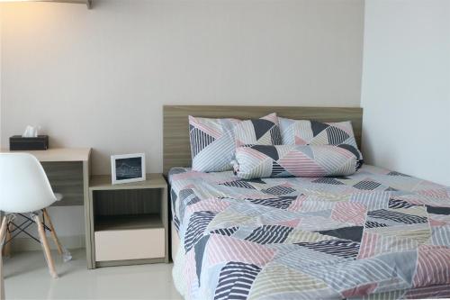 a bedroom with a bed with pillows and a desk at Apartemen Taman Melati Yogyakarta by ArFe Room in Sleman