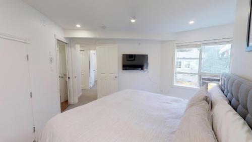 a white bedroom with a large bed and a window at Amazing Location with PRIVATE Hot Tub by Harmony Whistler in Whistler
