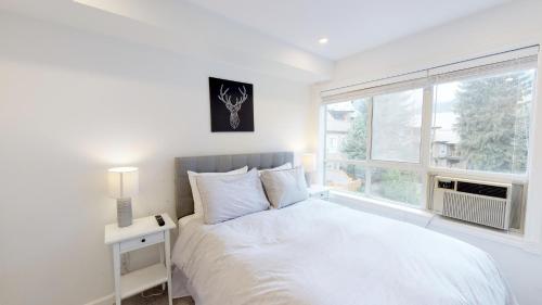 a white bedroom with a bed and a window at Amazing Location with PRIVATE Hot Tub by Harmony Whistler in Whistler
