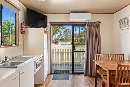 a kitchen and dining room with a table and a view of a porch at Discovery Parks - Moama West in Moama