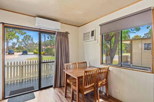 a dining room with a table and chairs and a balcony at Discovery Parks - Moama West in Moama