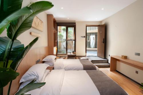 Zimmer mit 4 Betten und einer Pflanze in der Unterkunft Memory Garden House in Xi'an