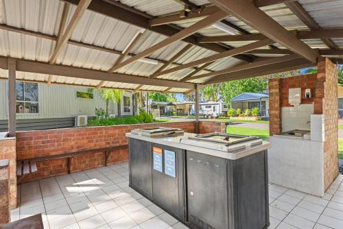 a patio with an outdoor kitchen under a wooden pergola at Discovery Parks - Moama West in Moama
