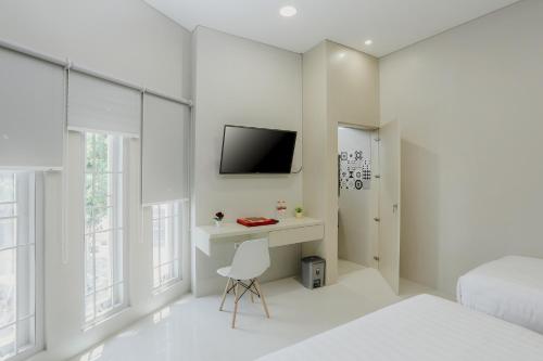 a white bedroom with a desk and a tv on a wall at House of Asiyah Syariah in Solo