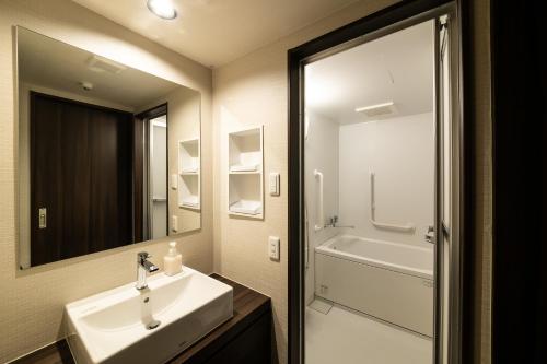 a bathroom with a sink and a mirror and a tub at Kyoto Central Inn in Kyoto