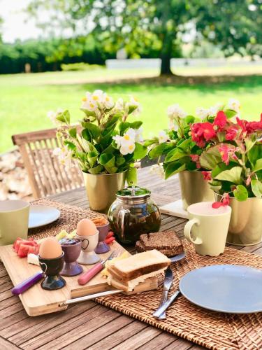 a table with eggs and sandwiches and flowers on it at Gîte de la Valière in Chevigny-en-Valière