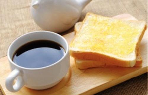 un pezzo di pane e una tazza di caffè su un tagliere di T'Luck House Resort a Haad Chao Samran