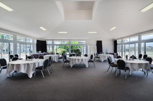 a banquet hall with white tables and chairs and windows at Mantra on Salt Beach in Kingscliff
