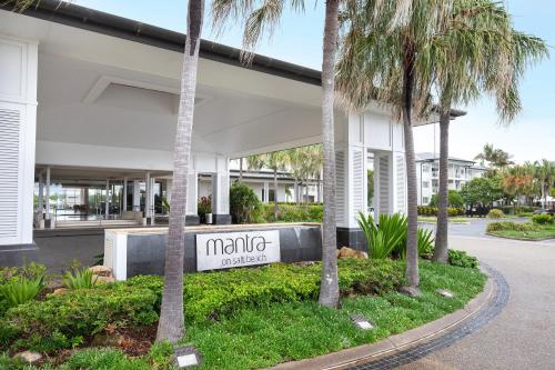 a sign in front of a building with palm trees at Mantra on Salt Beach in Kingscliff