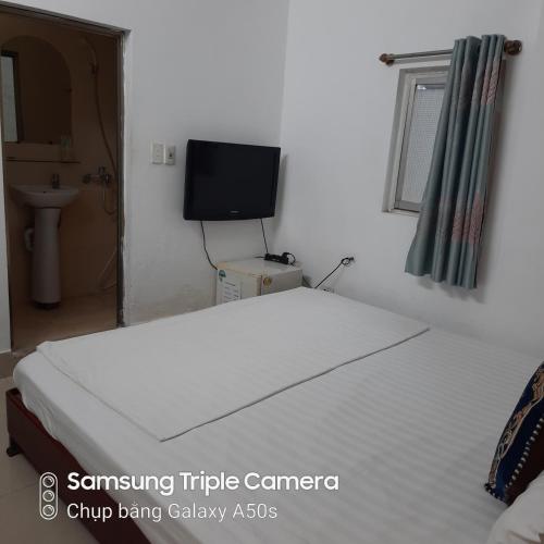 a white bed in a room with a tv at Hanoi Carina Hotel in Hanoi