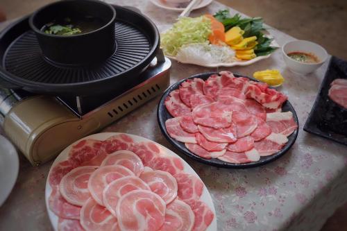 uma mesa coberta com pratos de carne ao lado de uma grelha em Promma Farm Resort em Ban Tat Ton (1)