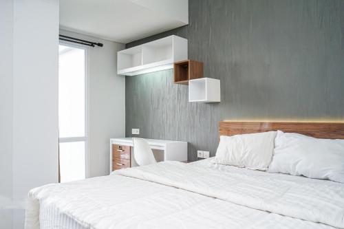 a bedroom with a white bed and a gray wall at Apartemen Taman Melati Yogyakarta by ArFe Room in Yogyakarta