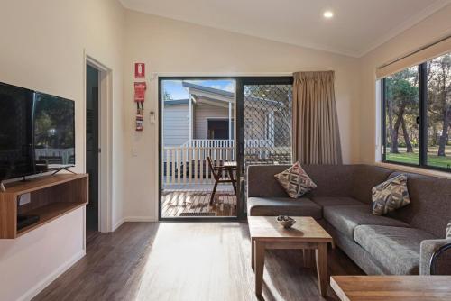 a living room with a couch and a tv at Discovery Parks - Pambula Beach in Pambula