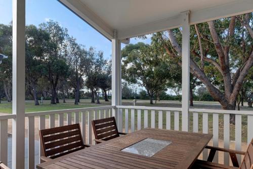 a wooden table and chairs on a porch with trees at Discovery Parks - Pambula Beach in Pambula