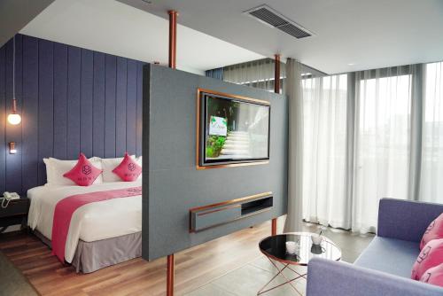 sypialnia z łóżkiem z różowymi poduszkami i telewizorem w obiekcie HOME Hotel w Ho Chi Minh