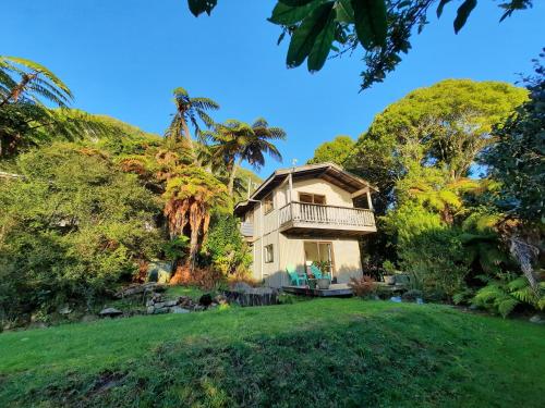 a house with a balcony on top of a yard at Te Nikau Retreat in Punakaiki