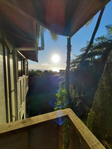 a view from a house balcony with the sun in the sky at Te Nikau Retreat in Punakaiki