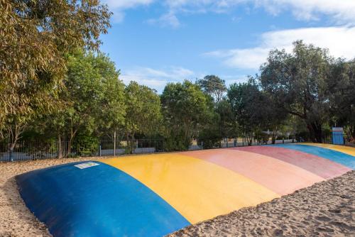 a rainbow colored skateboard ramp in a park at Discovery Parks - Pambula Beach in Pambula