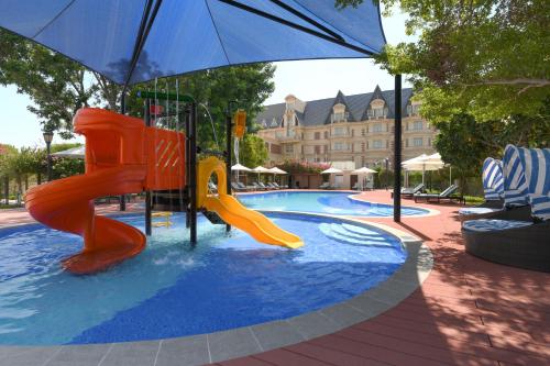 a playground with slides and an umbrella in a pool at Al Aziziyah Boutique Hotel By The Torch in Doha