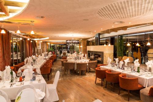 a restaurant with white tables and chairs and a fireplace at Stock Resort in Finkenberg