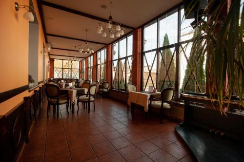 - un restaurant avec des tables, des chaises et de grandes fenêtres dans l'établissement Uyut Centralnaya Hotel, à Klintsy