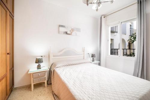 ein weißes Schlafzimmer mit einem Bett und einem Fenster in der Unterkunft Apartamento Conil Centro in Conil de la Frontera