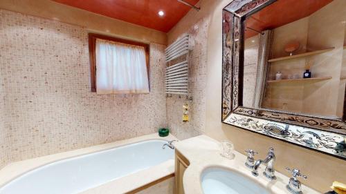 y baño con bañera, lavabo y espejo. en Aruons en St. Moritz