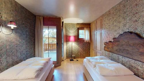 1 dormitorio con 2 camas y ventana grande en Aruons en St. Moritz