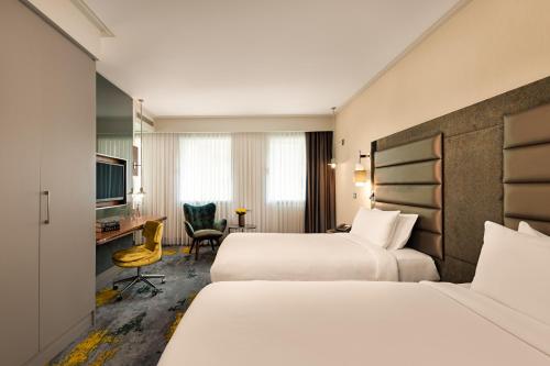 a hotel room with two beds and a desk at The Artisan Hotel Istanbul - MGallery Collection in Istanbul