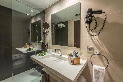 a bathroom with a sink and a mirror and a shower at Hotel Olot Centre in Olot