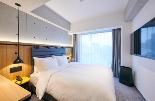 ein Schlafzimmer mit einem großen weißen Bett und einem Fenster in der Unterkunft ibis Styles Nagoya in Nagoya