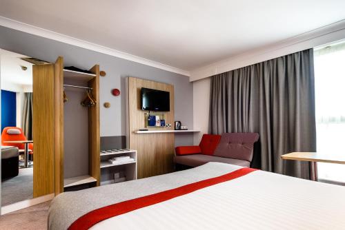 a hotel room with a bed and a couch at Holiday Inn Express London Stansted Airport, an IHG Hotel in Stansted Mountfitchet
