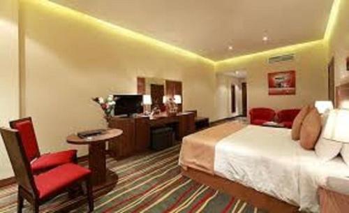 
a hotel room with a bed, chair, desk and a television at Al Khaleej Palace Deira Hotel in Dubai
