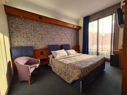 una camera d'albergo con un letto e una sedia di Hotel Sabra a Senigallia