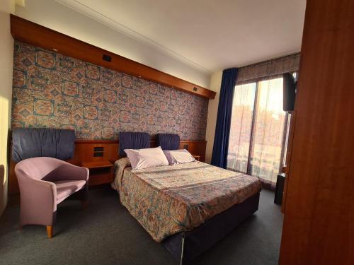 een hotelkamer met een bed en een stoel bij Hotel Sabra in Senigallia