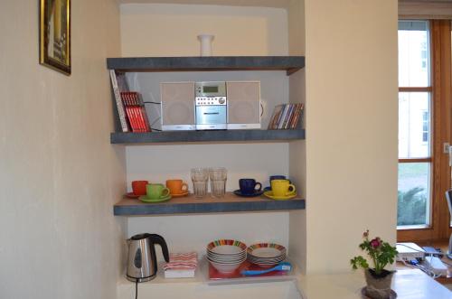 una cocina con estanterías, microondas y vajilla en Vilnius Collegium Apartment, en Vilna