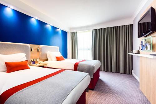 a hotel room with two beds and a flat screen tv at Holiday Inn Express London Stansted Airport by IHG in Stansted Mountfitchet