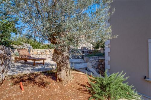a bench sitting under a tree next to a wall at Lučica 360 sea view suite in Nerezine